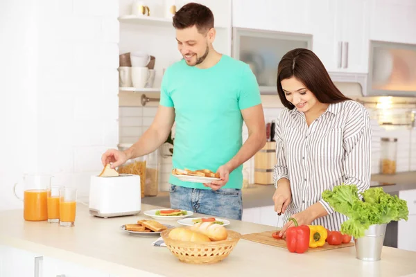 Jovem casal preparando café da manhã com torradas na cozinha — Fotografia de Stock