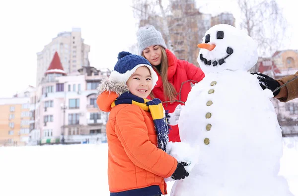 Glückliche Familie macht Schneemann im Park im Winterurlaub — Stockfoto