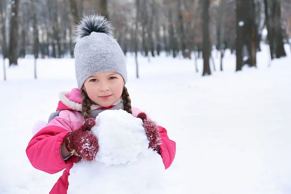 Nettes Mädchen macht Schneemann im Park im Winterurlaub — Stockfoto