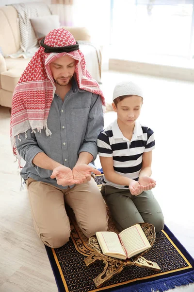 Muslim man praying with son at home Stock Image