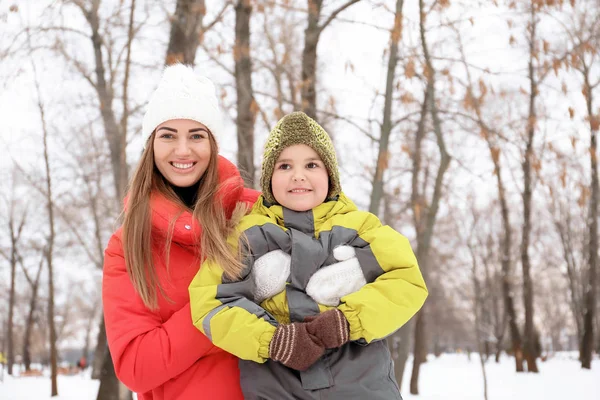 Šťastná žena se synem v zasněženém parku na zimní dovolenou — Stock fotografie