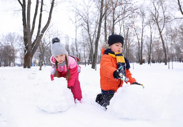 Glückliche Kinder basteln Schneemann im Park in den Winterferien — Stockfoto