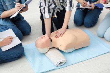 Group of people practicing CPR on mannequin at first aid class clipart