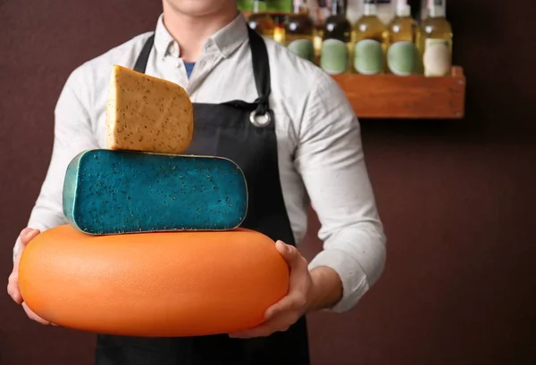 Young worker holding different cheeses in shop — Stock Photo, Image