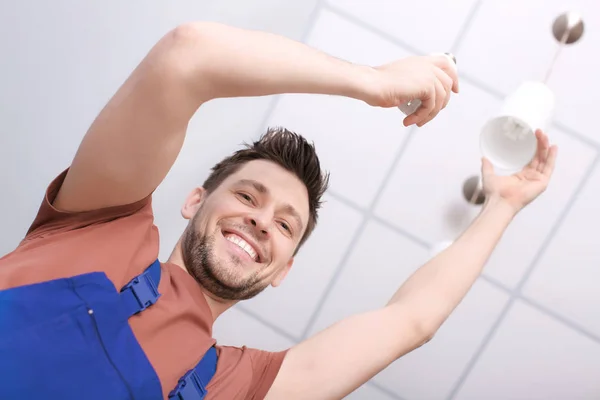 Man changing light bulb in lamp, indoors