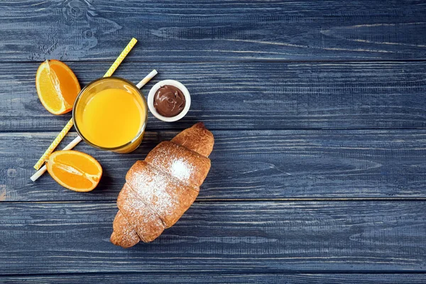Композиція зі свіжим смачним півмісячним рулетом та апельсиновим соком на дерев'яному фоні — стокове фото