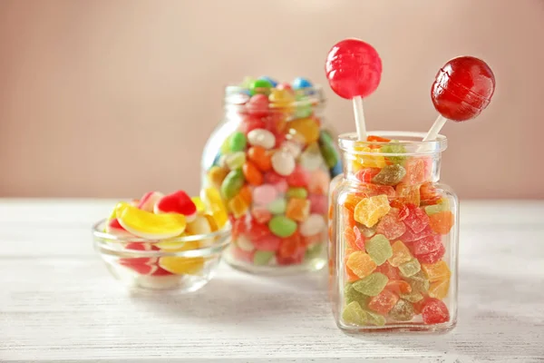 Glaswaren mit bunten Bonbons und gelingt auf dem Tisch vor hellem Hintergrund — Stockfoto