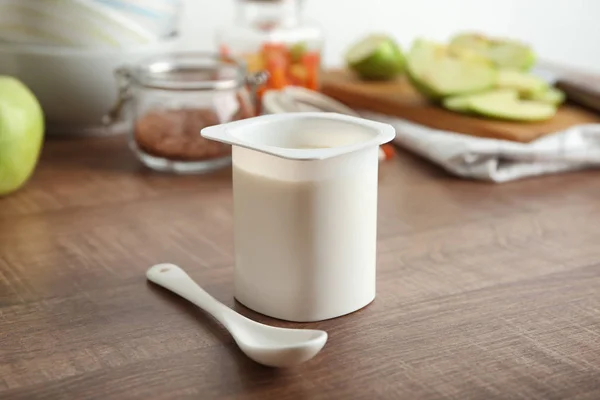 Copa de plástico de yogur delicioso en la mesa de madera — Foto de Stock