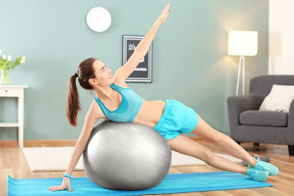 Mooie jonge vrouw doen fitness oefening met bal thuis — Stockfoto