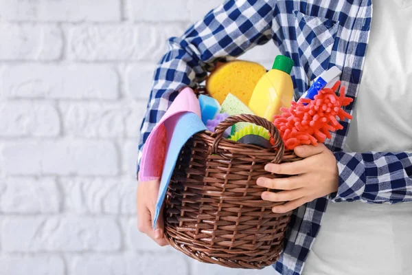 Panier femme avec fournitures de nettoyage sur fond de mur en brique — Photo