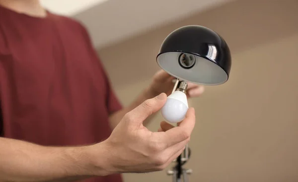 Man changing light bulb in lamp at home