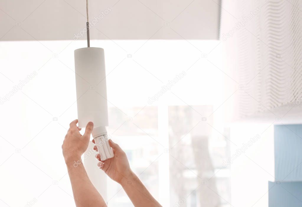 Man changing light bulb in lamp at home