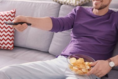 Genç adam evde kanepede televizyon izlerken