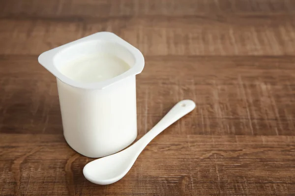 Plastmugg yummy yoghurt på träbord — Stockfoto