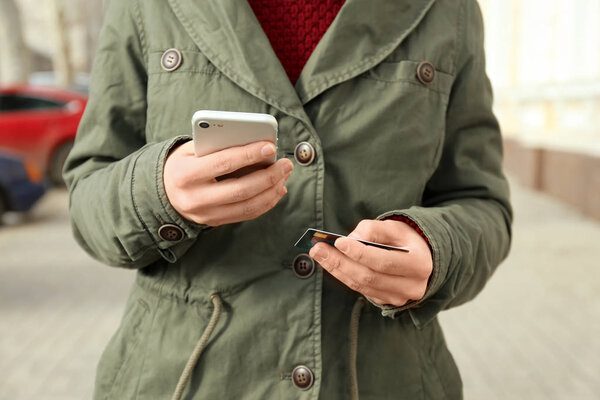 Женщина с кредитной картой с помощью смартфона на открытом воздухе
