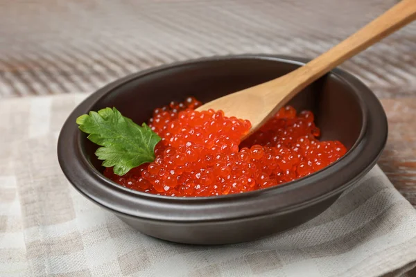 Tigela com delicioso caviar vermelho na mesa de madeira — Fotografia de Stock