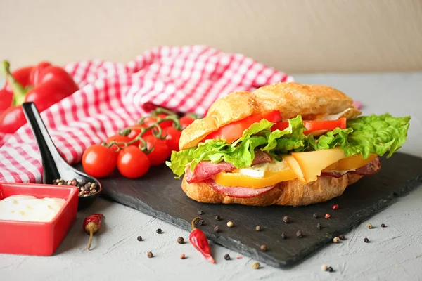 Sabroso sándwich de croissant en plato de pizarra — Foto de Stock