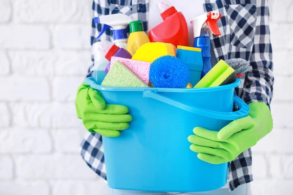 Vrouw met emmer met schoonmaak leveringen op bakstenen muur achtergrond — Stockfoto