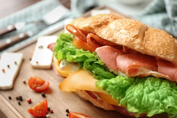 Tasty croissant sandwich on wooden board, closeup — Stock Photo, Image