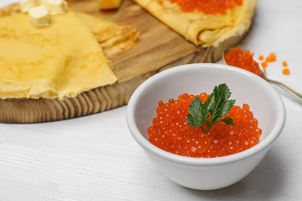 Cuenco con delicioso caviar rojo sobre mesa de madera blanca —  Fotos de Stock