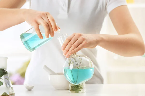 Woman pouring perfume oil into glass flask at table indoors — Stock Photo, Image