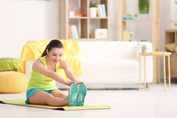 Krásná mladá žena dělá fitness cvičení doma — Stock fotografie