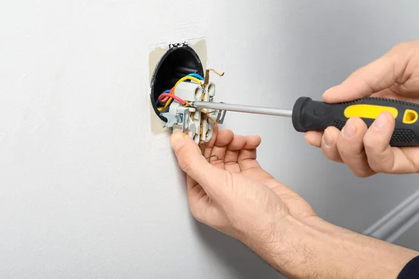 Electrician repairing socket on light wall — Stock Photo, Image