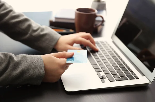 Жінка з кредитною карткою використовує ноутбук за столом — стокове фото