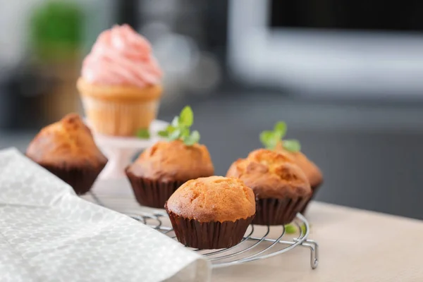 Cremalheira de refrigeração com cupcakes saborosos na mesa — Fotografia de Stock