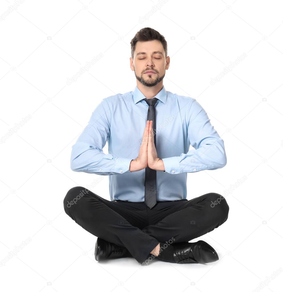 Young businessman meditating on white background