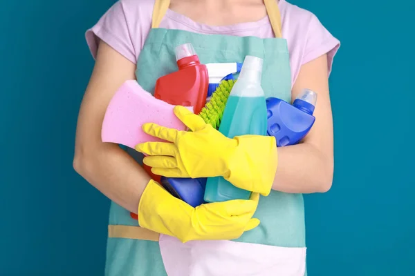 Woman holding cleaning supplies on color background — Stock Photo, Image