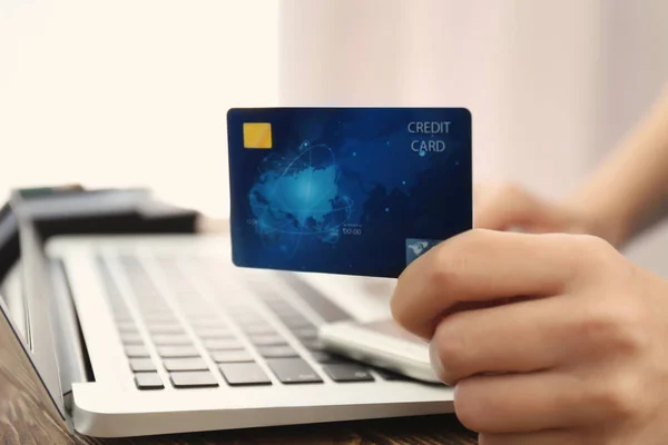 Woman holding credit card near laptop, closeup — Stock Photo, Image