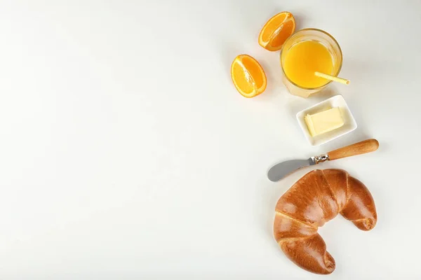Färska välsmakande crescent rulle, smör och apelsinjuice på vit bakgrund — Stockfoto