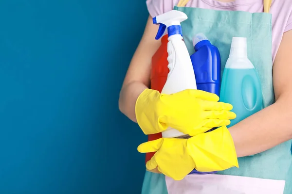 Woman holding cleaning supplies on color background — Stock Photo, Image