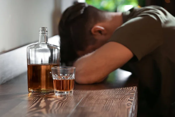 Butelki i kieliszki z piciem w pobliżu pijany mężczyzna — Zdjęcie stockowe