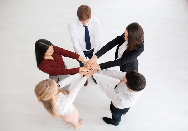 Människor sätter händerna tillsammans inomhus — Stockfoto