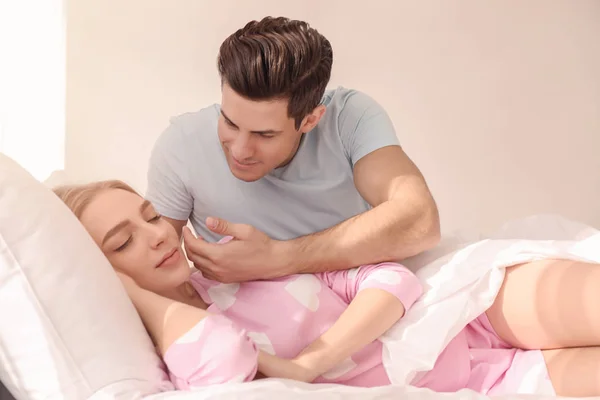 Ung man vaknar upp vackra hans flickvän i sängen hemma — Stockfoto