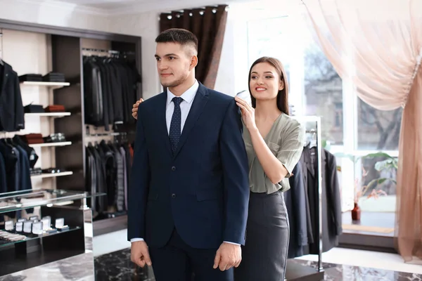 assistant helping man to choose suit