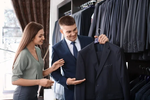 Assistente ajudando o homem a escolher terno — Fotografia de Stock