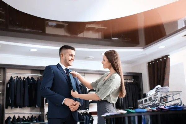 assistant helping man to choose suit