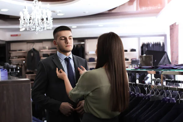 Assistente ajudando o homem a escolher terno — Fotografia de Stock