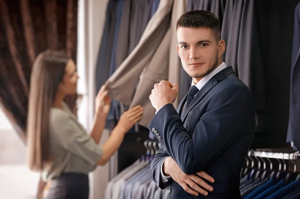 Assistente ajudando o homem a escolher terno — Fotografia de Stock