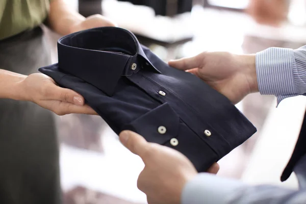 assistant helping man to choose shirt