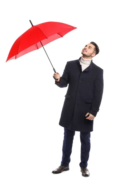 Hombre joven con abrigo cálido con paraguas rojo sobre fondo blanco — Foto de Stock