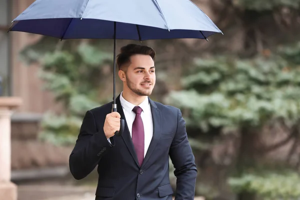Jovem em terno elegante com guarda-chuva escuro ao ar livre — Fotografia de Stock