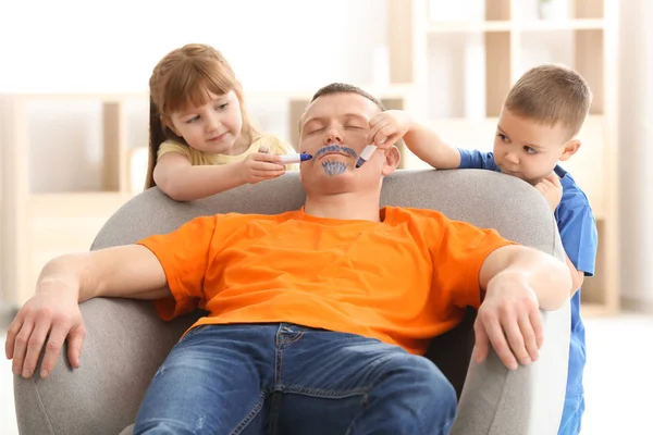 Mijn lieve kinderen schilderen van hun vaders gezicht terwijl hij slaapt. April fool's day prank — Stockfoto