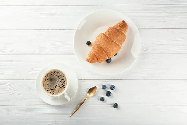 Croissant lezat dan secangkir kopi di atas meja kayu — Stok Foto
