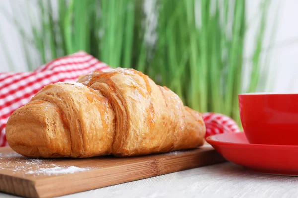 Wooden board with tasty croissant on table — Stock Photo, Image
