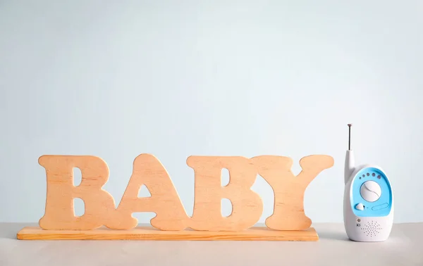 Monitor de bebé y letras de madera en la mesa contra el fondo de color — Foto de Stock
