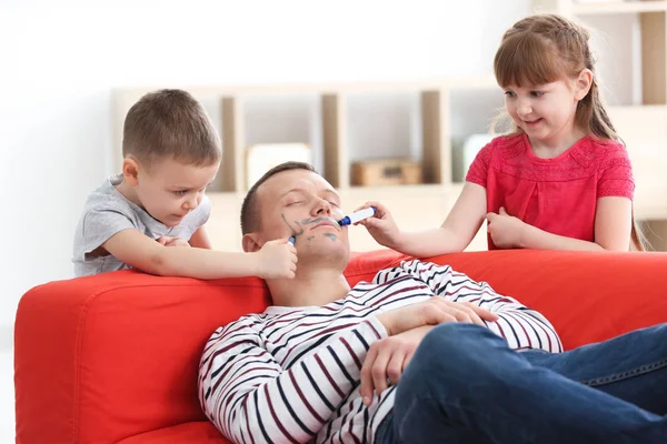 Mijn lieve kinderen schilderen van hun vaders gezicht terwijl hij slaapt. April fool's day prank — Stockfoto